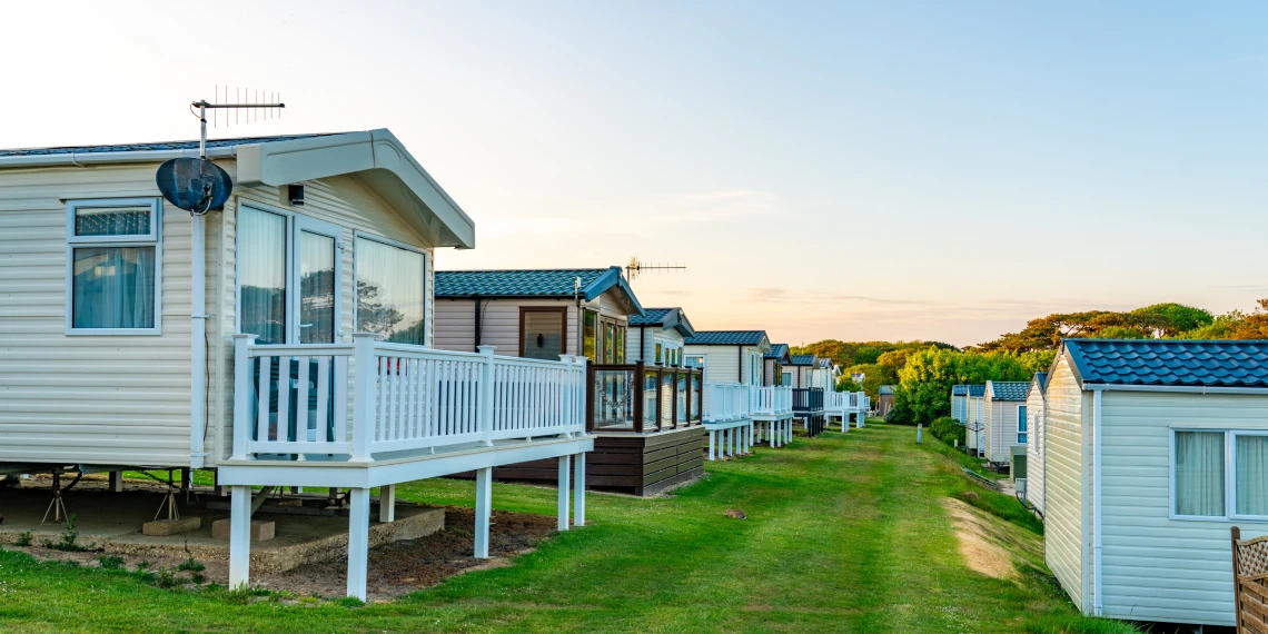 Row of mobile homes on grassy field.